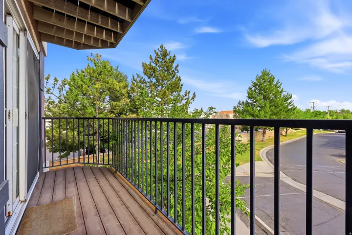 Private balcony featuring wood-finish flooring, black metal railing, and white double doors