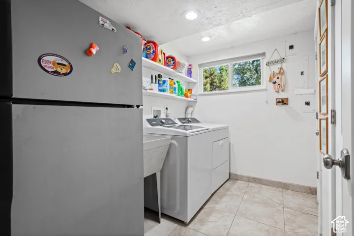 Utility room featuring a window, tile flooring, built-in shelving, and a laundry sink