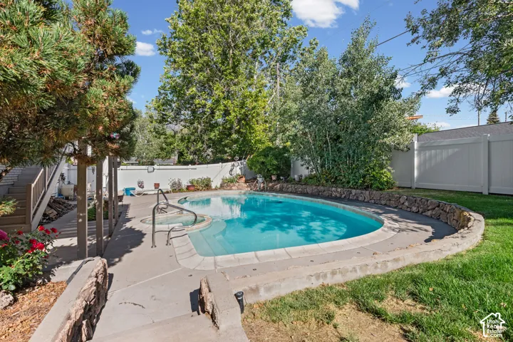 Outdoor swimming pool with integrated spa and concrete decking