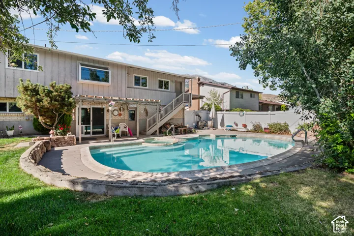 Backyard featuring an inground swimming pool with integrated spa and concrete coping
