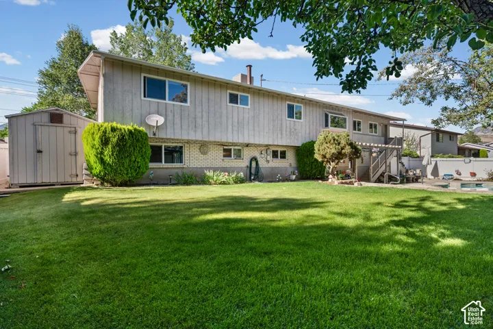 Expansive backyard featuring a lush lawn, a detached storage shed, and an inground swimming pool