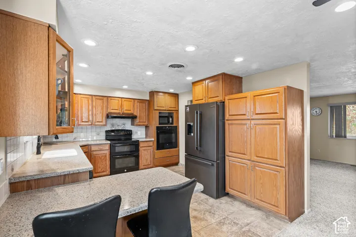 Kitchen featuring wood-finish cabinetry, speckled countertops, and a white subway tile backsplash