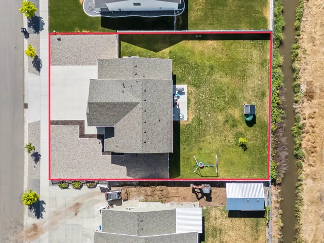 Expansive property featuring a large shingle-roofed residence, concrete driveway, and generous grassy yard