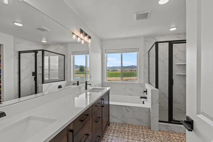 Modern bathroom featuring a double vanity with stone-finish countertops, wood-finish cabinetry, and contemporary black fixtures