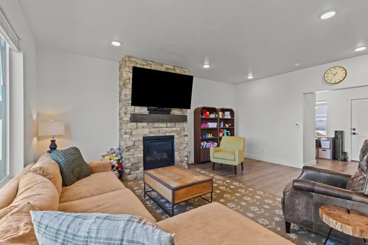 Living area featuring a stone-clad fireplace with a dark wood mantel, recessed lighting, and wood-finish flooring
