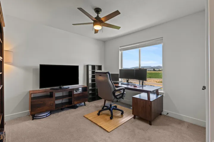 Bright room featuring a large window, neutral carpeting, and a ceiling fan with integrated lighting