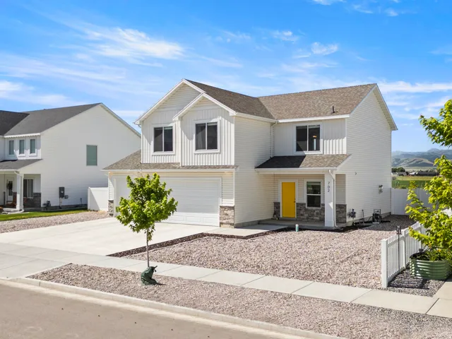 Two-story residence featuring white vertical and horizontal siding, a dark shingle roof, and stone facade accents