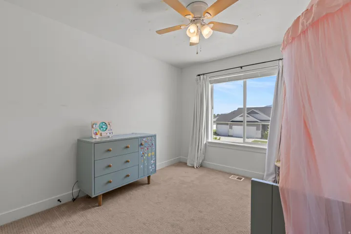 Room featuring a ceiling fan with integrated lighting, a large window with white trim, and light-colored carpeting