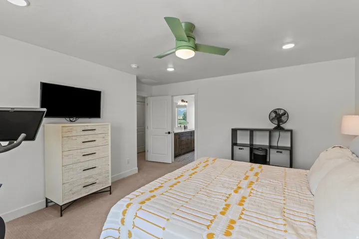 Bedroom featuring neutral carpeting, a ceiling fan with integrated lighting, recessed lighting, and a doorway leading to a bathroom