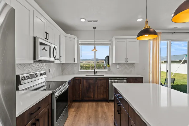 Modern kitchen featuring white upper cabinetry, dark wood-finish lower cabinetry, and light countertops