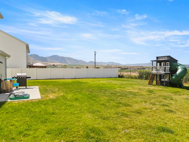 Expansive green lawn with a white privacy fence