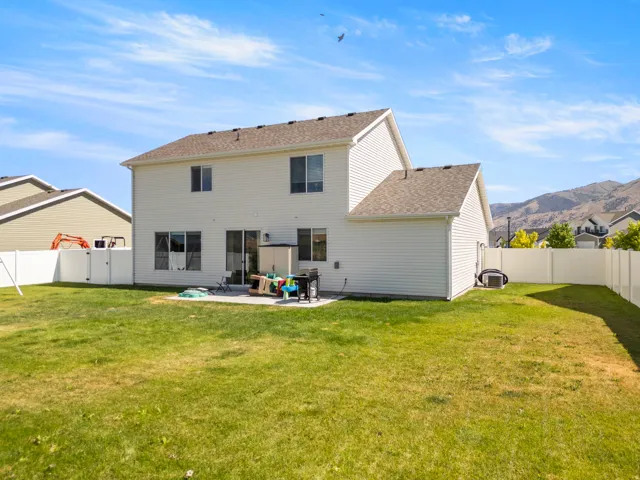 Spacious backyard featuring a concrete patio, white vinyl fencing, and a mountain backdrop