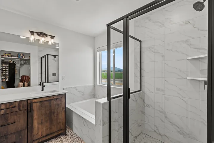 Contemporary bathroom featuring a walk-in shower with black-framed glass enclosure, white marble-look tile, and hexagonal floor tile