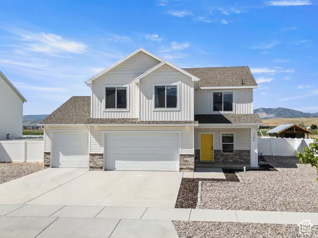 Contemporary two-story residence featuring light siding and stone veneer accents
