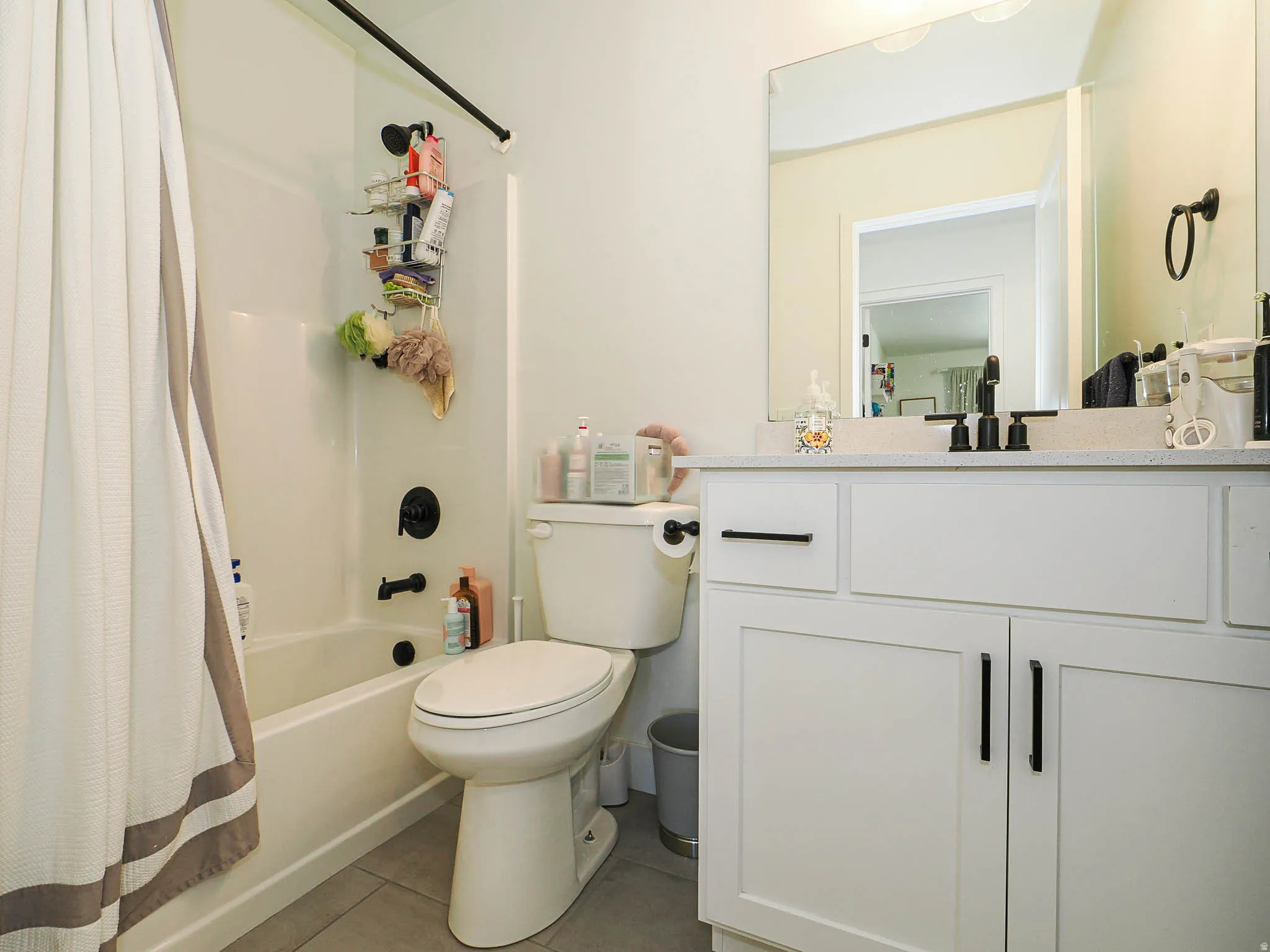 White shaker-style vanity with matte black hardware, a light-toned countertop, and an undermount sink