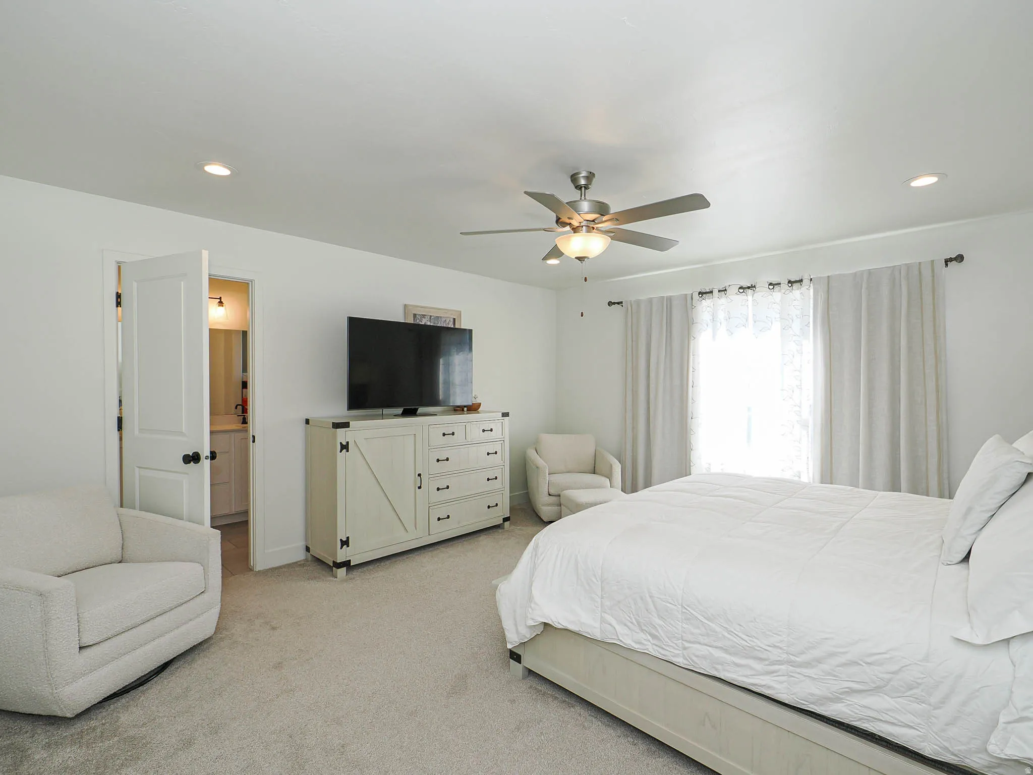 Recessed lighting, ceiling fan with integrated light, and large window with curtain rods