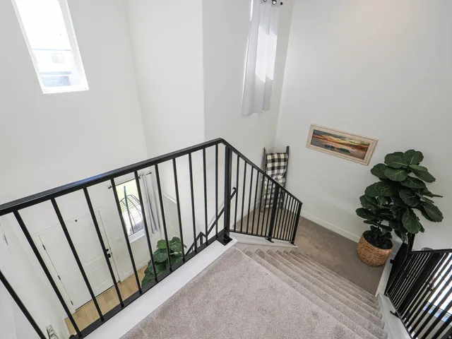 Multi-level interior featuring a carpeted staircase with contemporary black metal railings