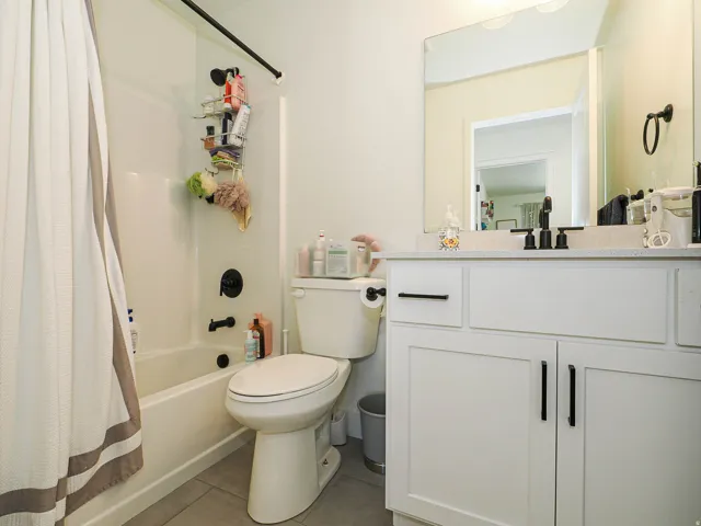 White shaker-style vanity with matte black hardware, a light-toned countertop, and an undermount sink