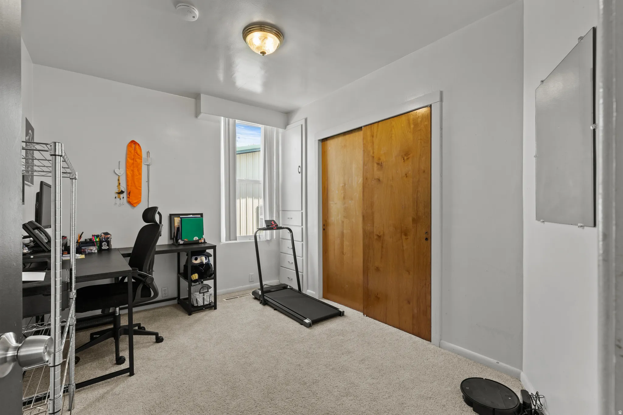 Carpeted room with a full-height window, a ceiling-mounted light fixture, and a closet with wood-finish sliding doors