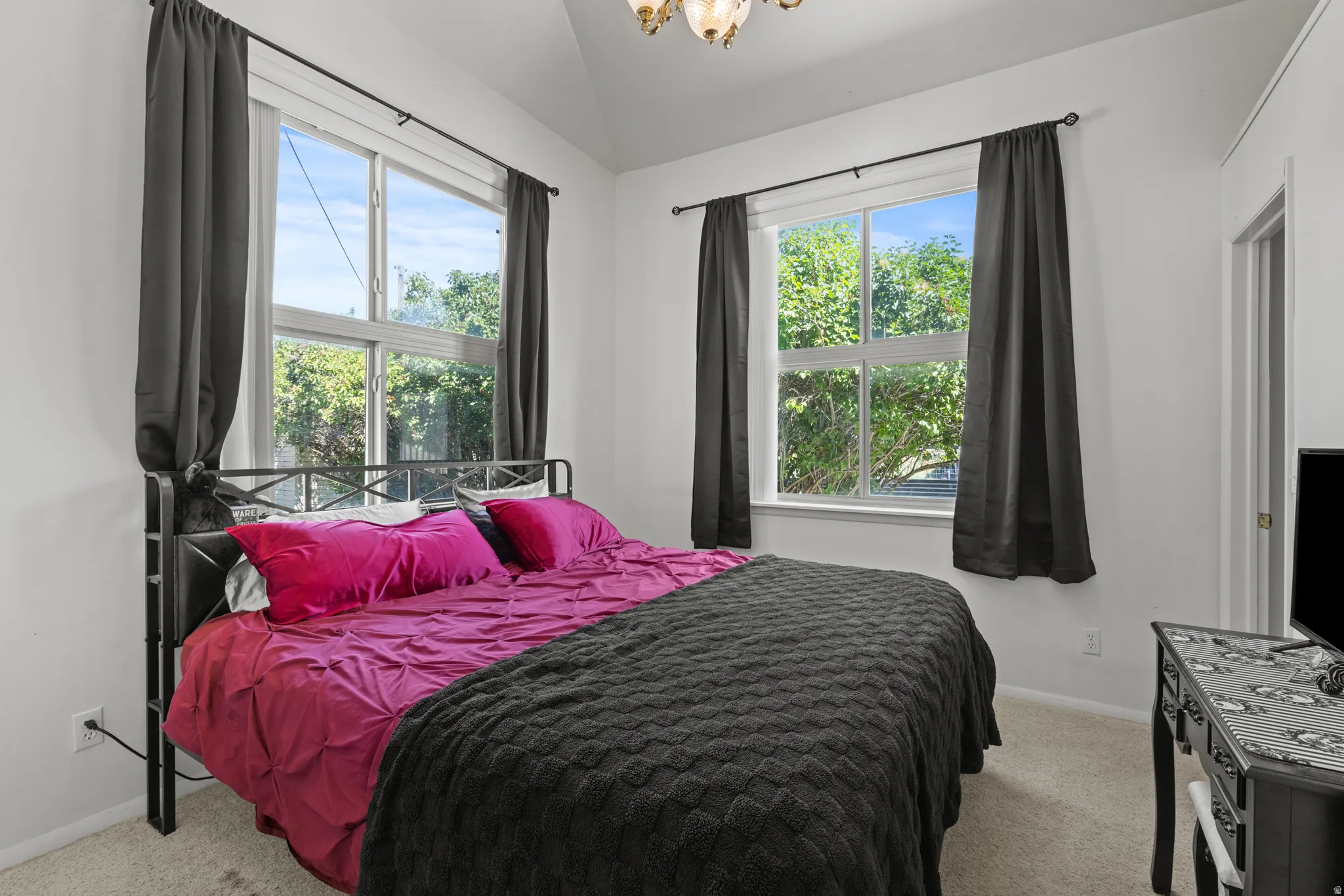 Bright bedroom featuring two large windows, a vaulted ceiling, recessed lighting, and light-toned carpeting