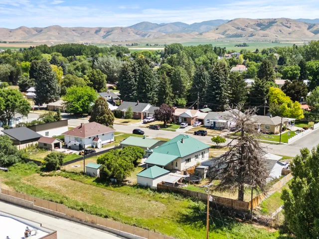 Aerial perspective showcasing a neighborhood setting with established homes, mature trees, and distant mountains