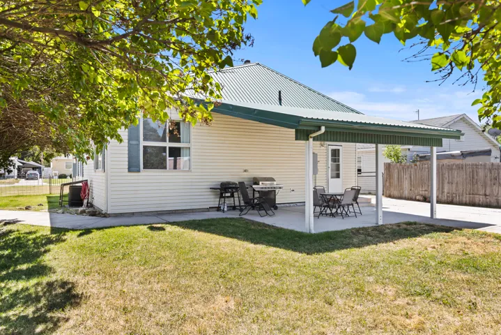 Rear exterior featuring a covered patio, light-toned siding, and a green metal roof