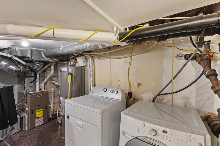 Basement utility area featuring a water heater, furnace, and exposed ductwork