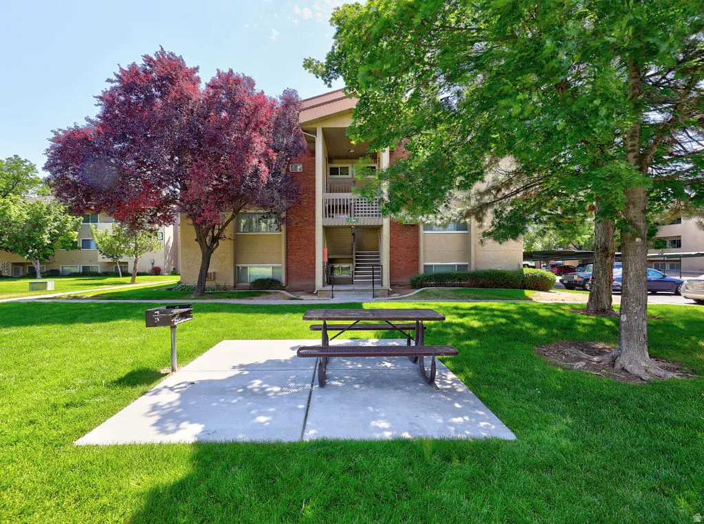 Lush green lawn featuring a concrete patio with a picnic table and a built-in barbecue grill
