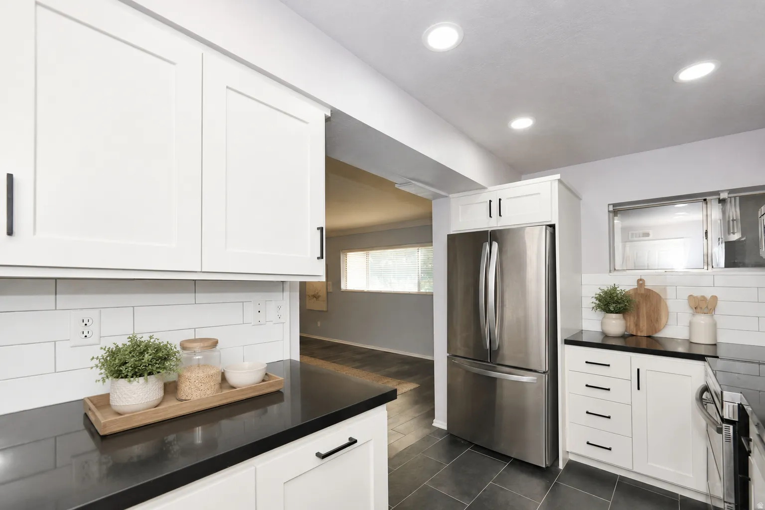 Kitchen featuring white shaker cabinetry, dark countertops, white subway tile backsplash, and recessed lighting