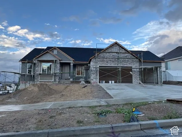 Single-story residence featuring a multi-material exterior of stone veneer and horizontal siding, a gabled roofline, and a three-car garage with a concrete driveway