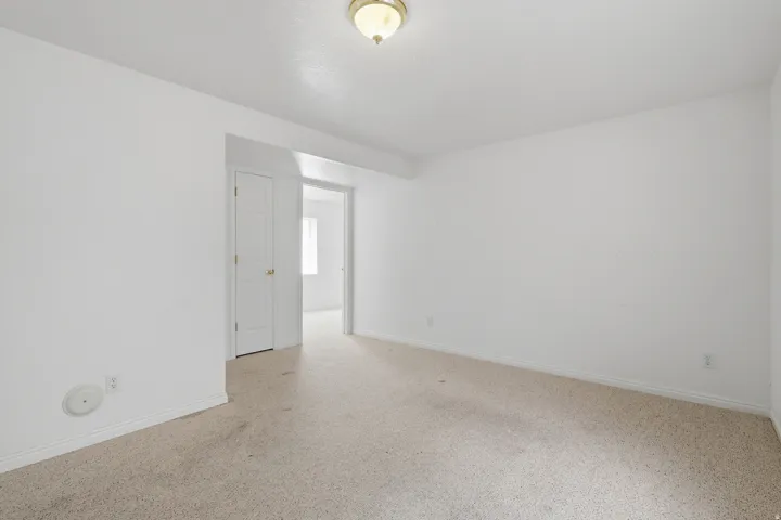 Bright, light-filled bedroom featuring neutral carpet flooring, white walls, and recessed ceiling lighting
