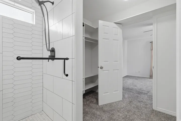 Primary Bathroom Suite with Walk-In Shower and Dual Vanity LayoutSpa-inspired walk-in shower featuring white subway tile walls, black metal fixtures, and a rainfall showerhead