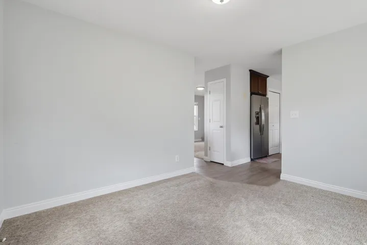 Spacious bedroom showcasing neutral wall finishes, neutral-toned carpet flooring, and abundant natural light