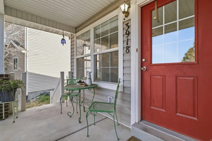 Covered porch with concrete flooring and a red paneled entry door