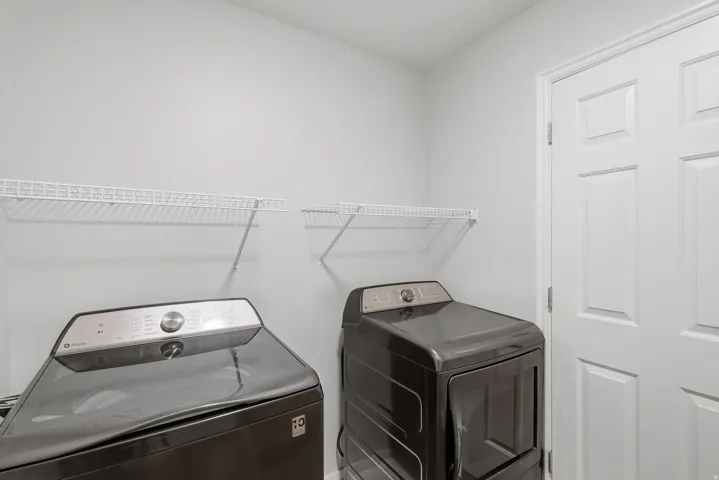 Dedicated laundry room featuring wire shelving, white six-panel closet doors, and space for full-size washer and dryer units