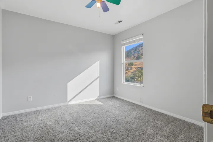 Neutral wall color, carpeted flooring, window with blinds, and ceiling fan