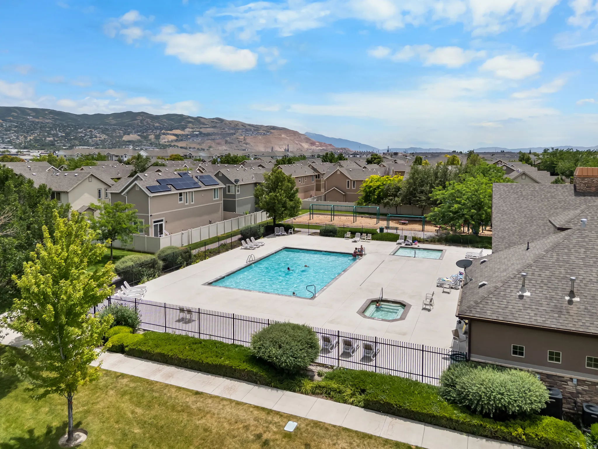 Community swimming pool with an integrated spa, surrounded by a paved deck and privacy fencing