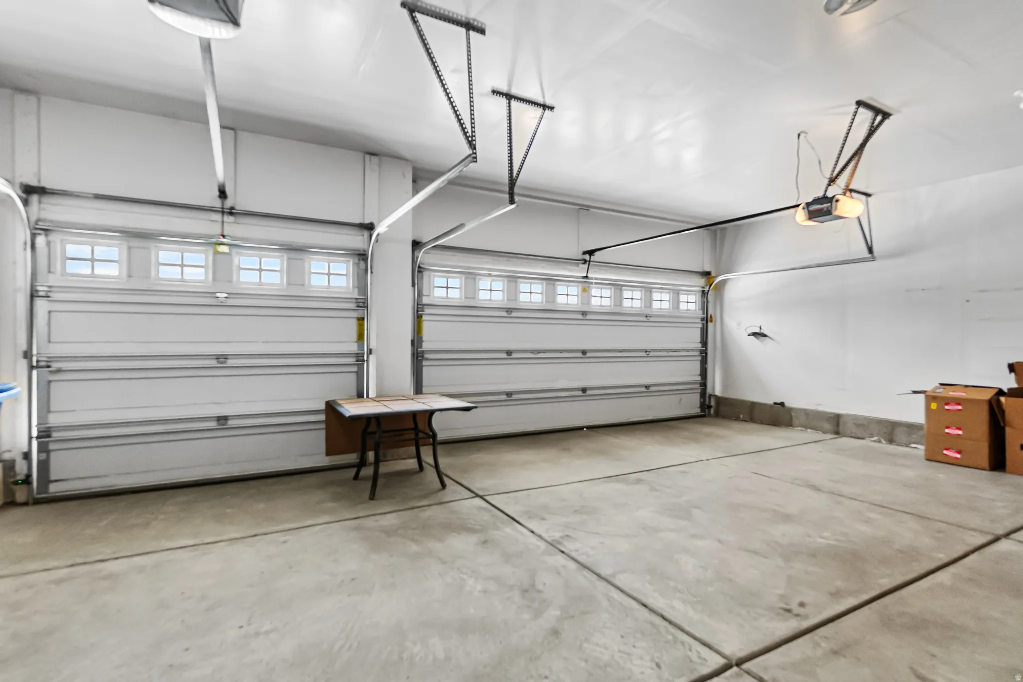 Two-car garage featuring concrete flooring, white walls, and two overhead garage doors with window inserts