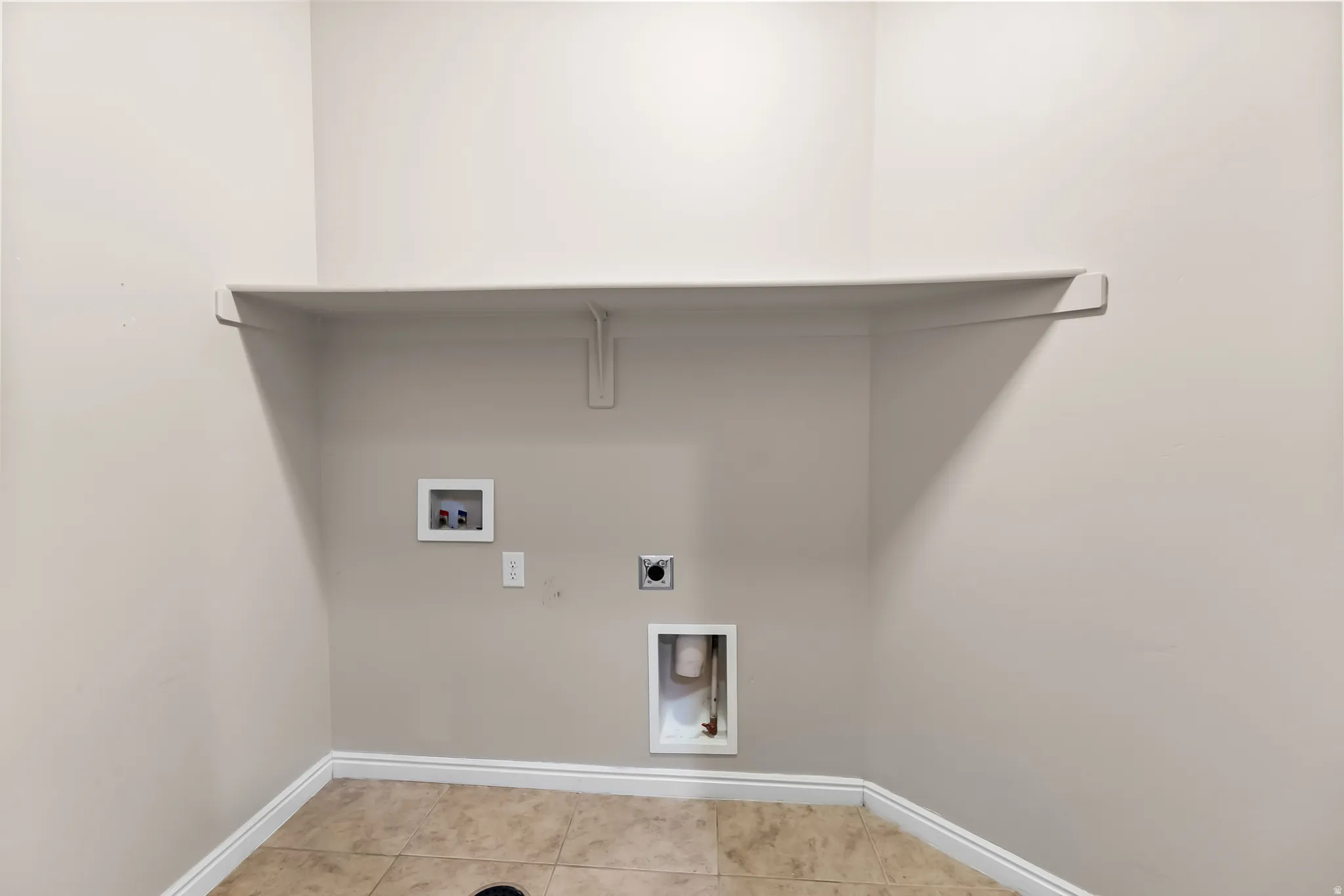 Dedicated laundry area featuring a built-in shelf, neutral wall tones, and ceramic tile flooring