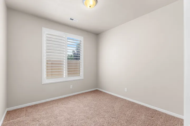 Neutral-toned interior room featuring light brown carpeting and white baseboards