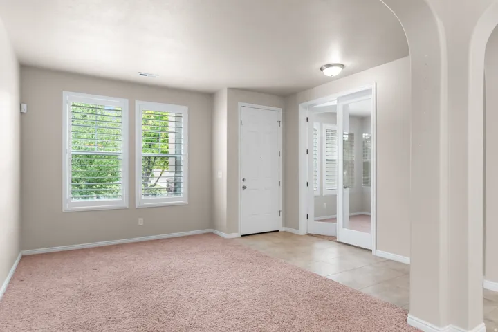 Entryway featuring light-toned walls, two framed windows with white louvered shutters, and a white entry door