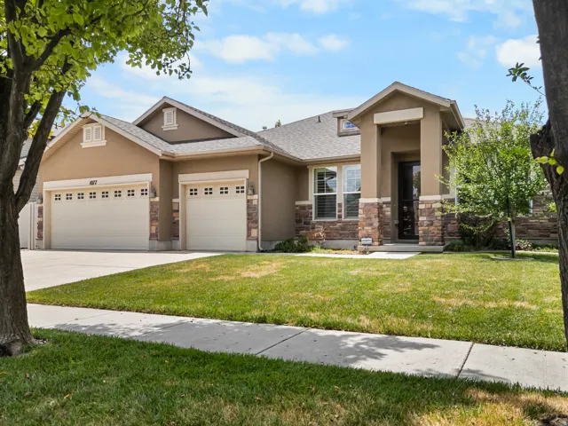 Stucco exterior with stone veneer accents, multi-pane garage doors, covered entry, and a concrete driveway