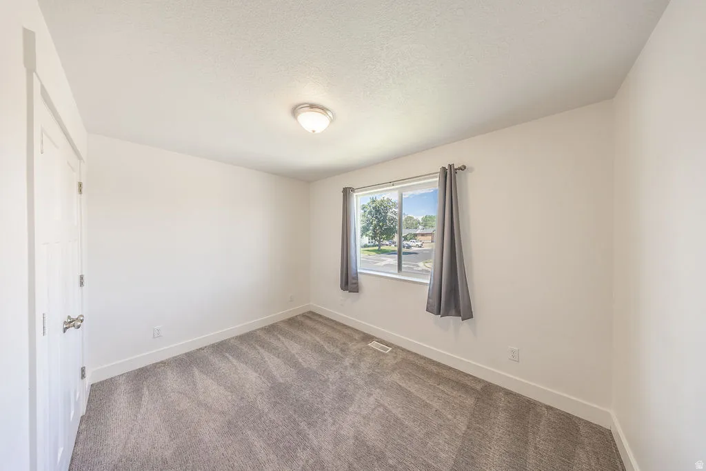 Bedroom #3.  Light wall color.  Light carpet.  Natural light through window.