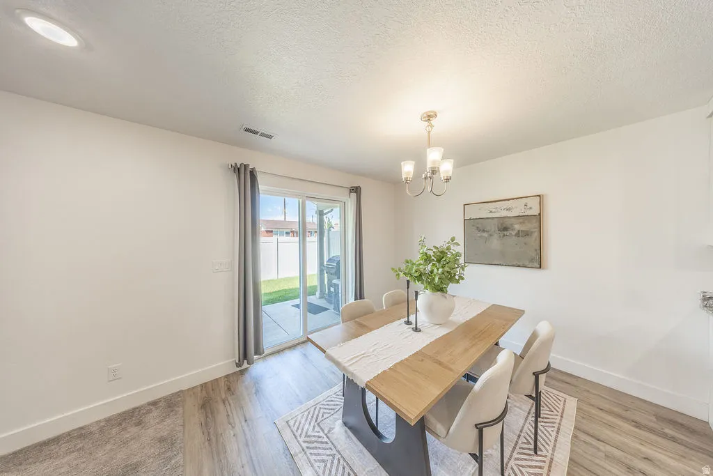 Dining area featuring LVP flooring, a contemporary chandelier, and a sliding glass door providing access to an outdoor patio