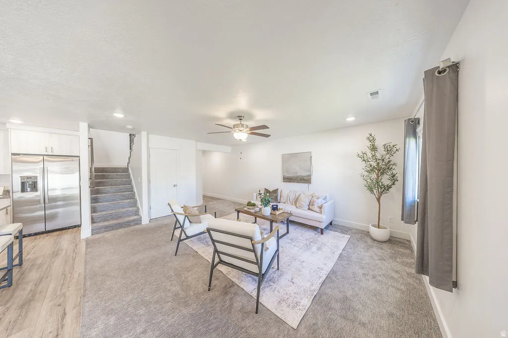 Spacious living area featuring light-toned carpeting and recessed lighting