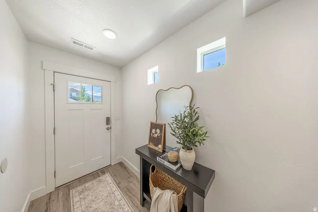 Entryway with a white paneled door featuring multiple glass lites, LVP flooring, two high-set square windows, recessed ceiling lighting, and light color walls.