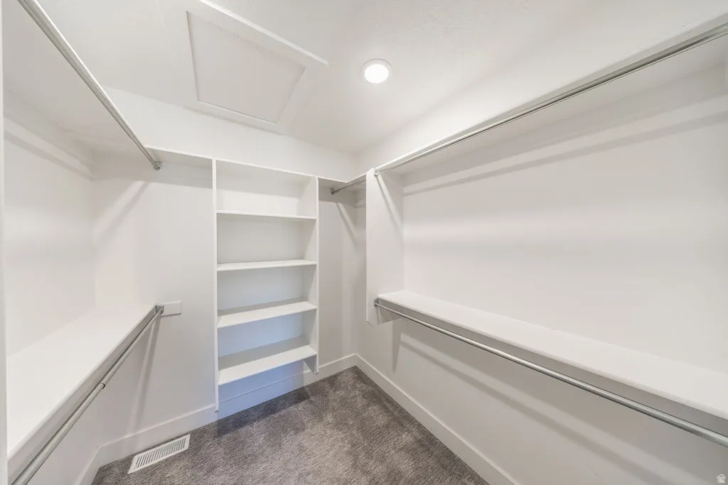 Walk-in closet featuring built-in shelving, multiple hanging rods, and recessed lighting