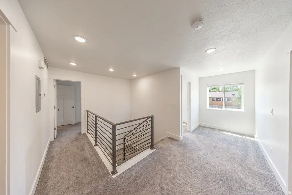 Hallway.  Flex space to the right by window. Light grey carpet.  Natural light.  Recessed lighting.