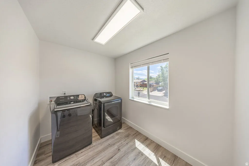 LARGE laundry room with LVP flooring, a window with blinds, and a ceiling-mounted rectangular light fixture