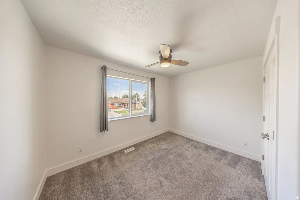 Bedroom #2.  Ceiling fan.  Light colored carpeting.  Closet doors on right.  White walls.